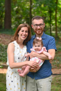 Ally Berman and Michael Godin standing and holding daughter Mira