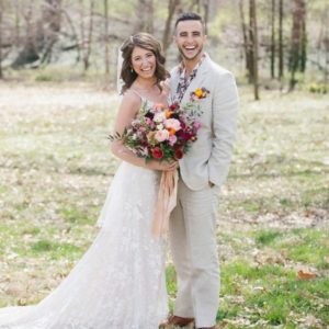 bride holds flowers and stands next to her groom on wedding day