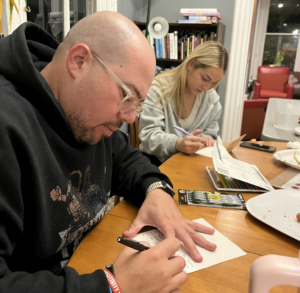 Two people sitting at a table writing letters